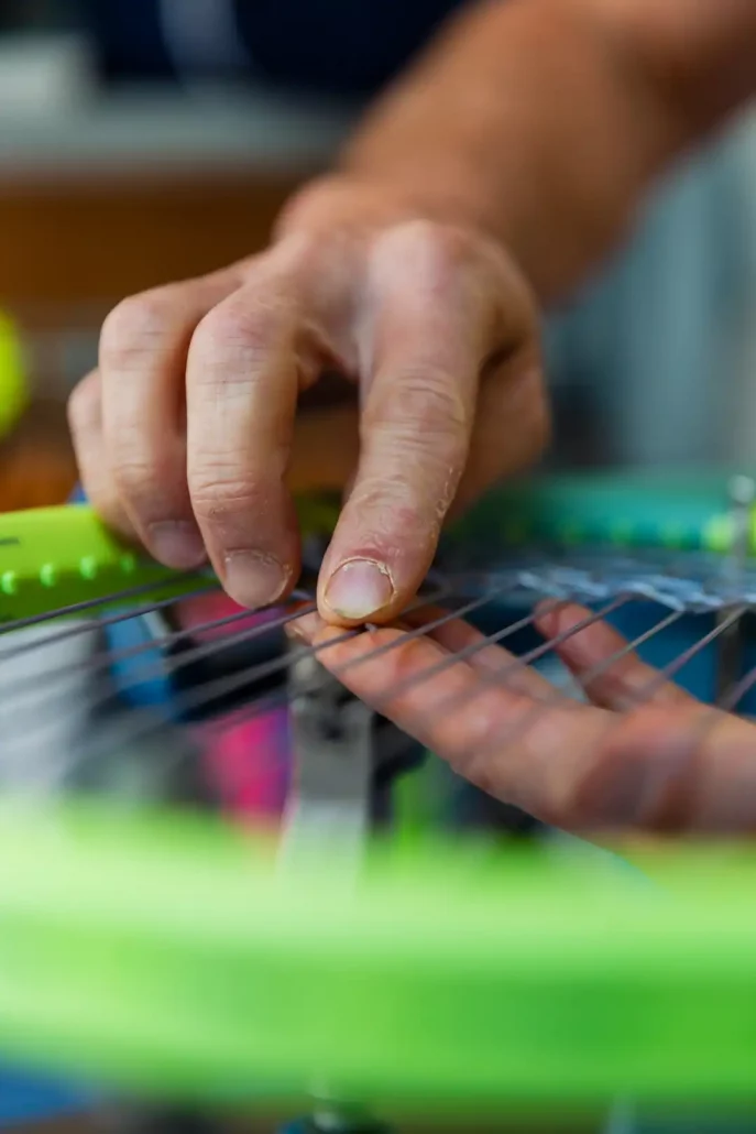 Photo avec gros plan sur une raquette qui est en train d'être cordée.